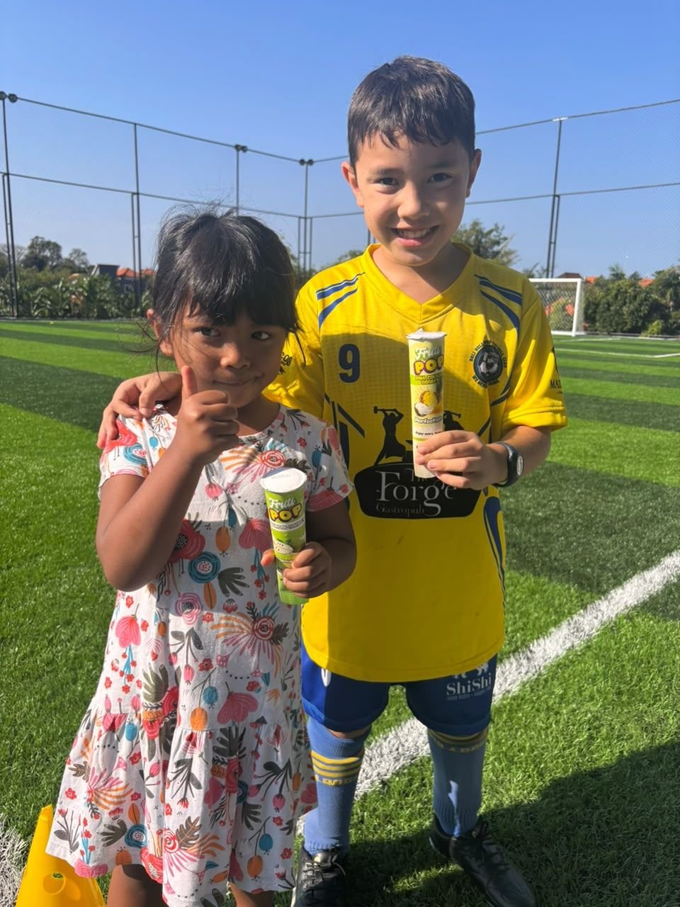 Two children with Fruti Pops on a football pitch